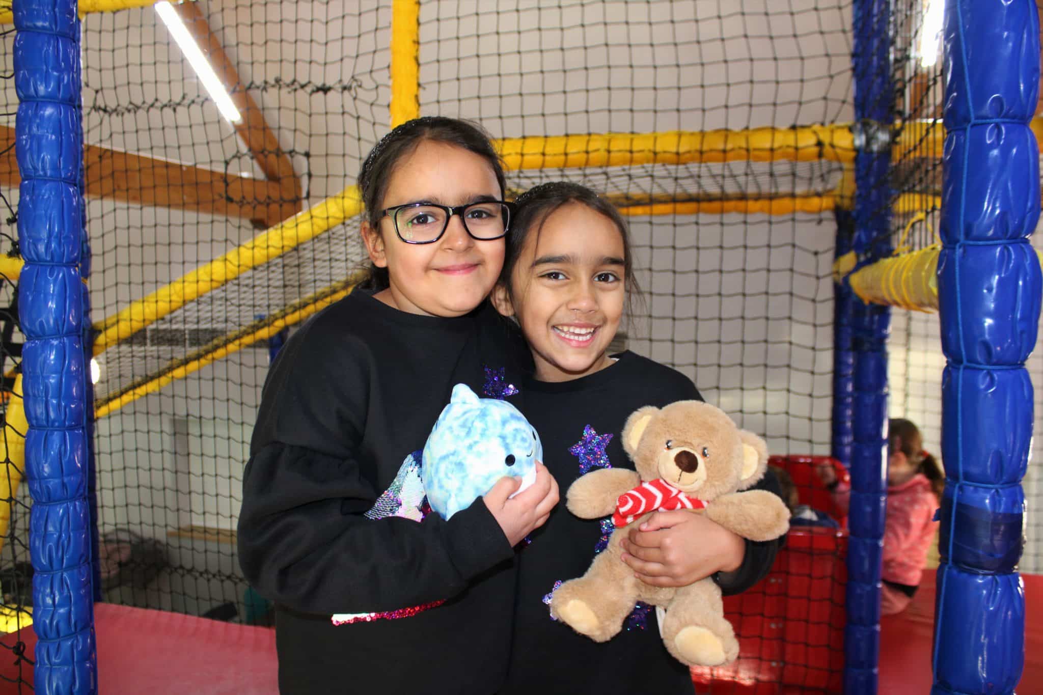 Two kids hugging and holding plushies at the soft play area