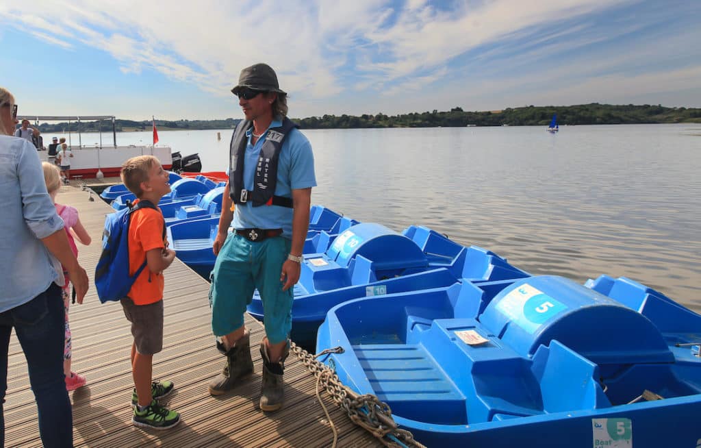 Bewl Water worker talking to family in front of pedalos