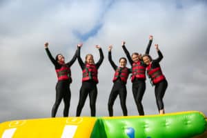 5 people with their hands in the air on a wibit inflatable