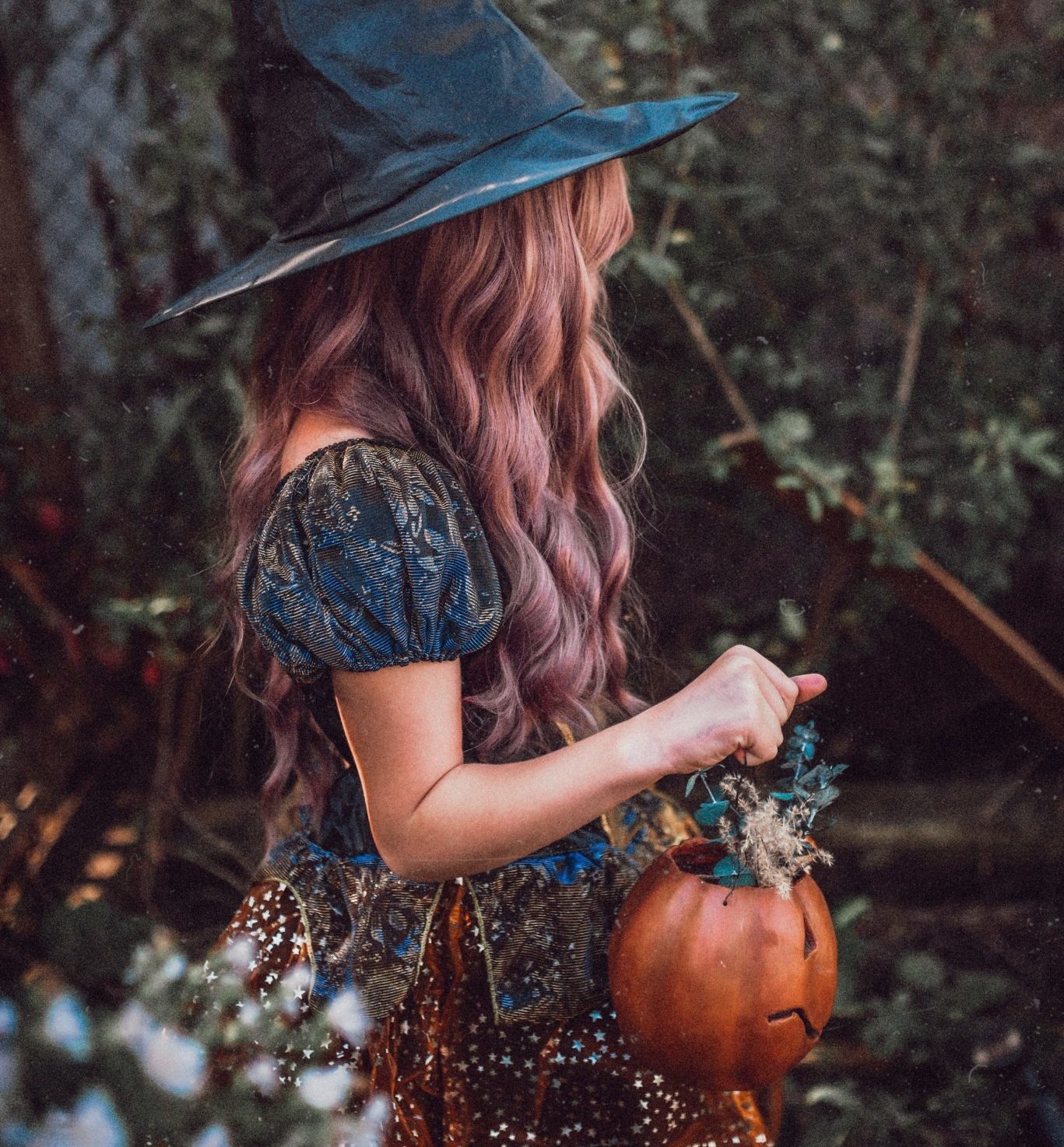 Girl with witch costume holding a pumpkin