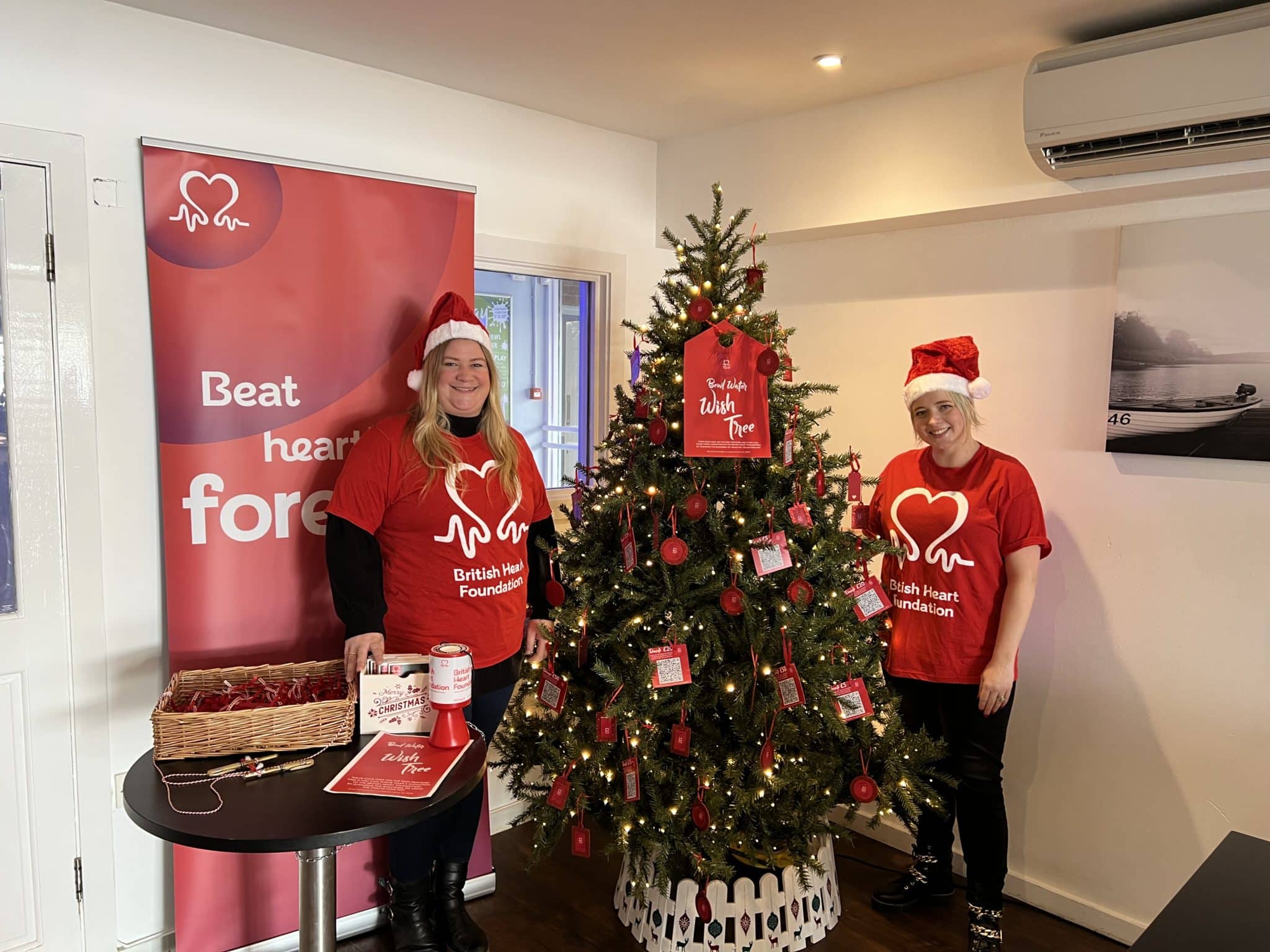 British Heart Foundation volunteers next to a Christmas tree