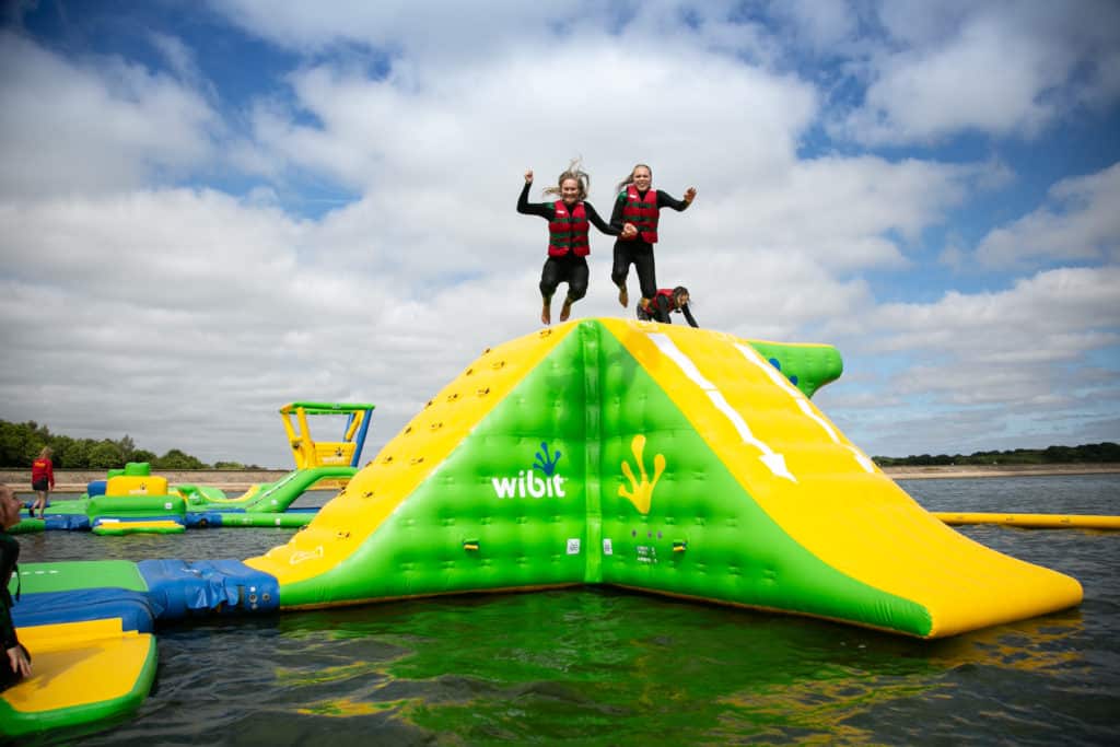 Two girls jumping together from bewl aqua park inflatable