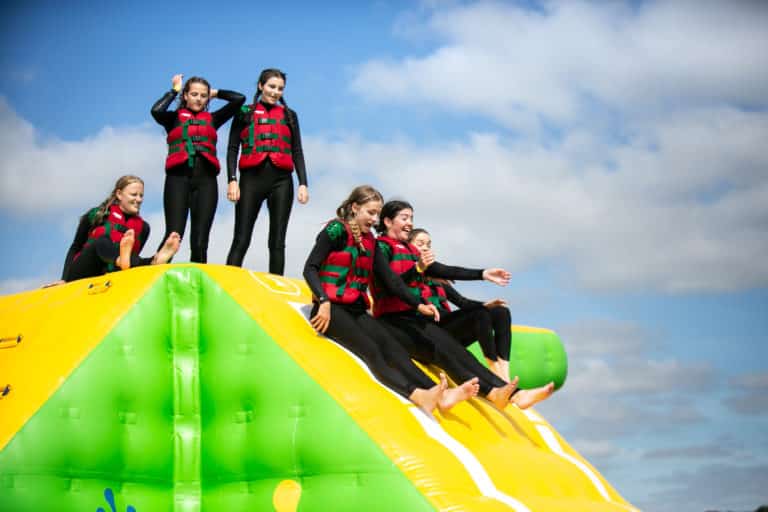 Three people sliding down the Aqua Park slide at Bewl Water