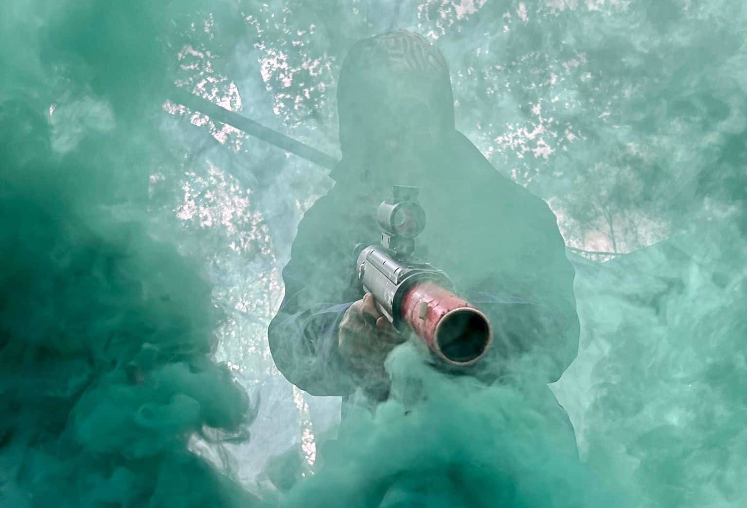 Person holding a gun walking through smoke