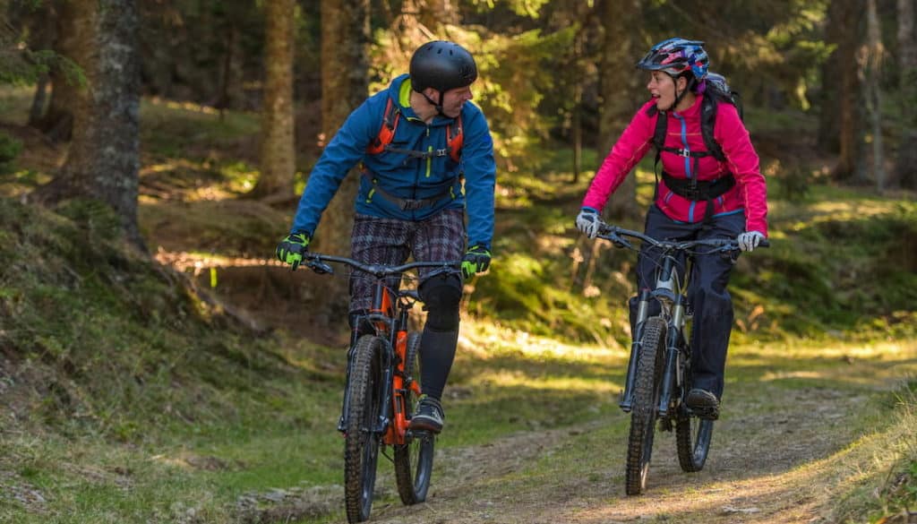 Two people riding bikes and wearing helmets