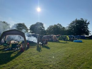 Families enjoying a camping holiday at Bewl Water, Kent with a BBQ set up under the sun.
