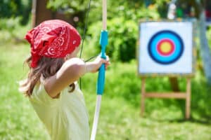 Child taking part in an outdoor archery taster session at Bewl Water, a popular destination for family-friendly summer activities in Kent.